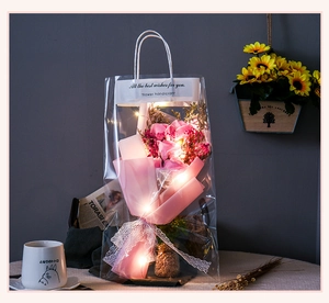 Detail of pink soap rose bouquet in transparent gift bag with warm LED fairy lights