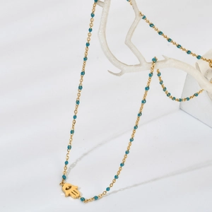Détail du collier main de Fatma dorée avec perles bleues sur support de corail