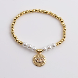 Bracciale elastico con perline dorate, perle bianche e ciondolo a forma di malocchio lucido