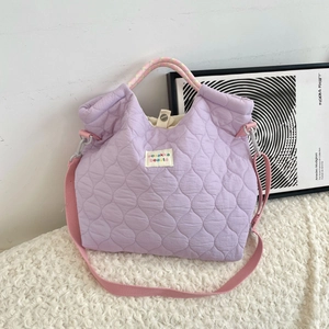 Detail van de paarse gewatteerde draagtas met roze geweven riem en merklabel op zacht pluche