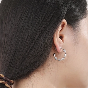 French style wavy silver twist hoop earrings on model showing minimalist irregular design