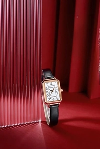 Detail of square rose gold watch with artistic numerals and black leather strap