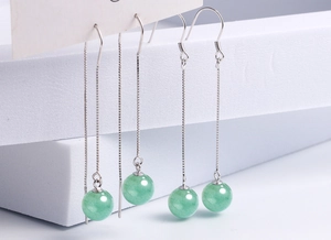 Detail view of long S925 silver chain earrings with pale green jadeite beads on white block