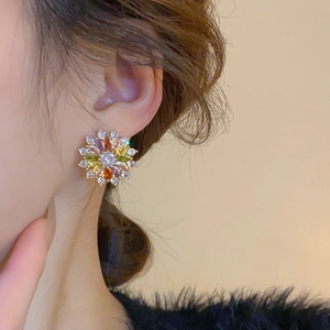 Close-up of a colorful flower stud earring with zircon stones on a model's ear