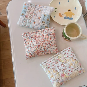 Quilted floral makeup bags in three patterns displayed on a white table in a cozy scene