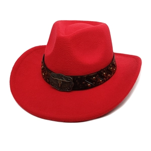 Détail d'un chapeau de cow-boy rouge avec boucle en métal tête de taureau et bande animale