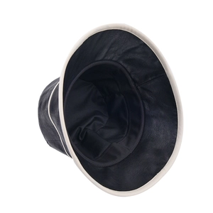 Detail view of black leather bucket hat featuring contrast white piping and wide brim texture