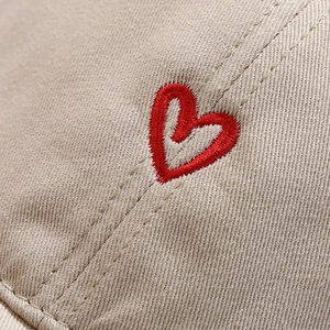 Front view of beige cotton baseball cap featuring high-quality red heart embroidery detail