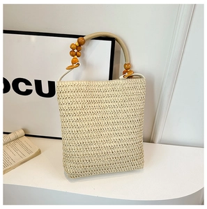 Close-up of the elegant woven straw handbag featuring a handcrafted wooden bead handle