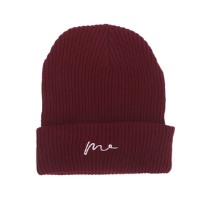 Close-up of wine red ribbed knit beanie featuring white 'me' cursive letter embroidery