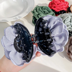 Macro detail of large purple rose fabric hair claw clip with strong metal spring