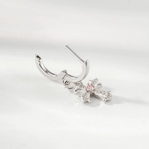 Silver cross drop earrings with pink cubic zirconia on a minimalist textured background