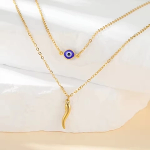 Detail of gold double layer necklace with blue evil eye and Italian horn charms