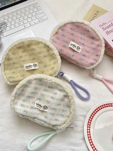 Three plush lamb wool seashell cosmetic bags in pink, yellow and white with rope handles