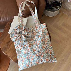 Detail of floral print cotton tote bag with matching scrunchie on a rustic wooden table