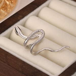 Macro shot of 925 sterling silver snake ear cuff with scale texture on wooden jewelry box