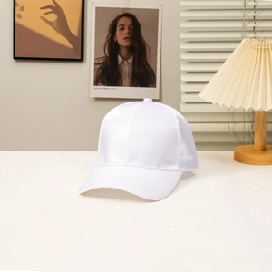 Close-up of white silk-textured baseball cap with satin finish in a minimalist home setting