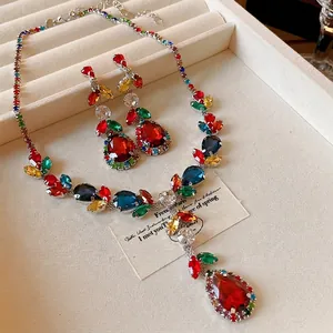 Colorful leaf drop rhinestone necklace and earring set on a beige jewelry display