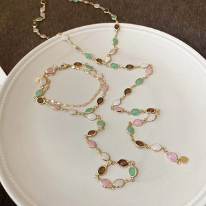 Detail view of resin gemstone necklace and heart pendant bracelet on ceramic tray