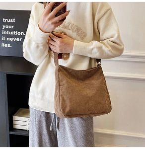 Brown corduroy shoulder bag with front pocket shown on a model in a modern interior