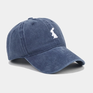 Close-up of white rabbit embroidery on vintage washed navy blue cotton baseball cap