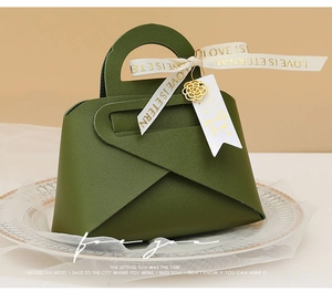 Detail of dark green leather wedding candy box with gold charms and Love is Eternal ribbon