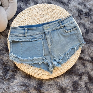 Dettaglio degli shorts in denim azzurro con orlo sfilacciato su tappeto di paglia