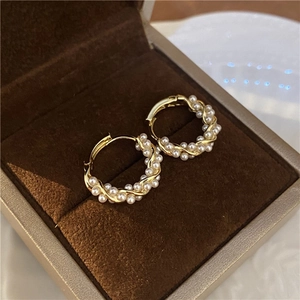 Close-up of gold-plated twisted pearl hoop earrings presented in a luxury velvet jewelry box