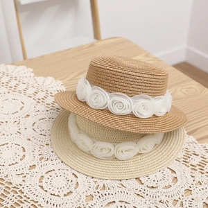 Elegante zomerse strohoeden met witte kanten rozen voor kinderen en moeders op strand.