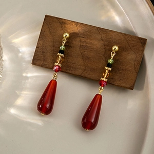Detail of vintage teardrop earrings with beads on a dark wood block in a ceramic tray