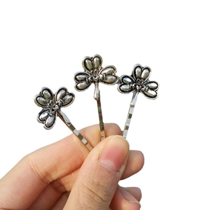 Three-piece set of vintage silver dragonfly hair clips shown in a hand for size reference