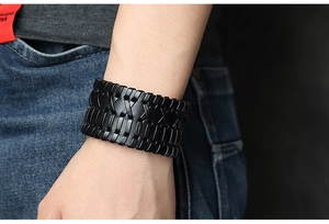 Detailed view of a men's black woven leather wide bracelet worn in a punk rock style