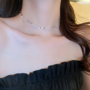 Primo piano della collana curva con zirconi scintillanti sul collo con finitura argento