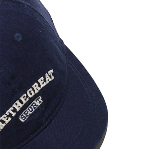 Detailed close-up of white letter embroidery on navy blue cotton baseball cap fabric