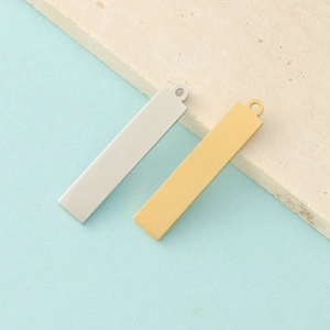 Mirror polished gold and silver rectangular stainless steel pendants on a stone surface