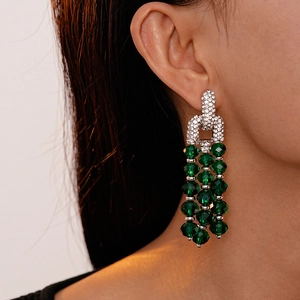 Close-up of green crystal tassel earrings with sparkling rhinestones on model's ear