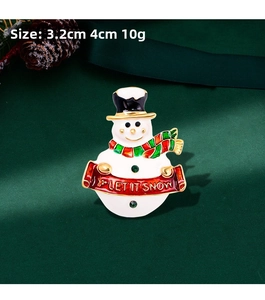 Detail view of snowman brooch with Let It Snow banner on dark green background