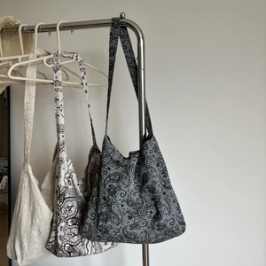 Detailed view of linen hobo bags in solid cream and paisley patterns on hangers