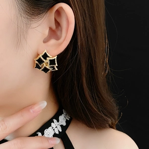 Detail view of vintage gold-rimmed black square earrings worn by a female model