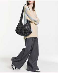 Detail of black faux leather tote with metal buckles and punk-style rivets on straps