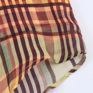 Gros plan sur une chemise en lin à carreaux avec tissage orange et détails de l'ourlet