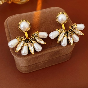 Detail view of retro fan-shaped earrings with pearls and crystals on brown velvet case