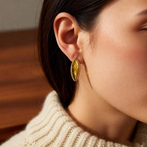 Detailed close-up of a marquise yellow crystal earring on a model with gold beaded border