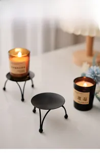 Detail of minimalist black metal candle holder with tripod legs in a cozy home setting