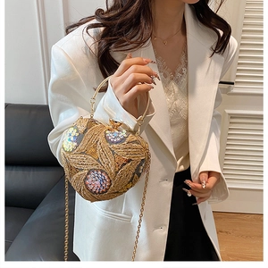 Detailed view of sequined embroidery on gold evening bag with metal chain and handle