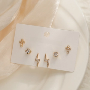Close-up of 18K gold plated earring set with cross, square zircon and lightning designs