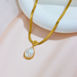 Elegant gold teardrop pendant on a sleek snake chain over soft pink silk fabric