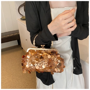 Close-up of champagne gold sequin handbag with elegant metal handle and chain strap