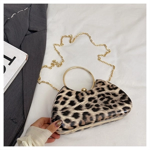 Detail view of leopard print evening clutch with gold circular handle and chain strap