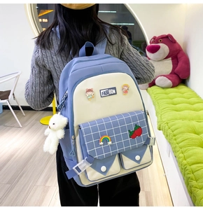 Detail of blue and white plaid backpack with cute patches and plush bear charm accessory